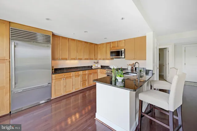 a open kitchen with granite countertop a refrigerator a sink and a large window