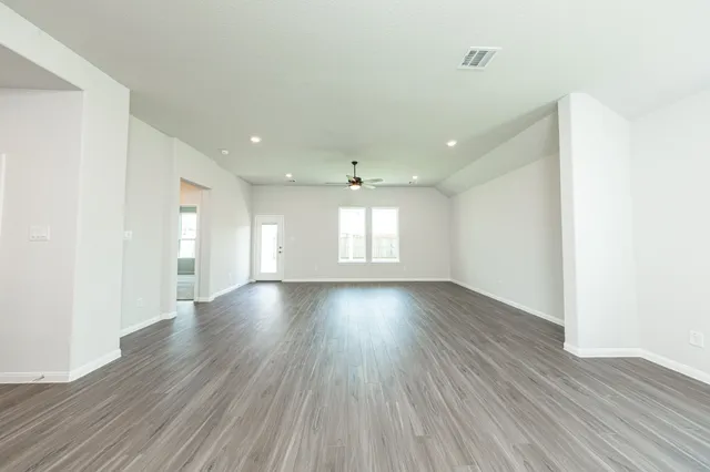 an empty room with wooden floor and windows