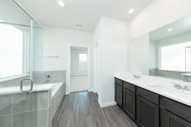 a spacious bathroom with a granite countertop sink a mirror and a bathtub