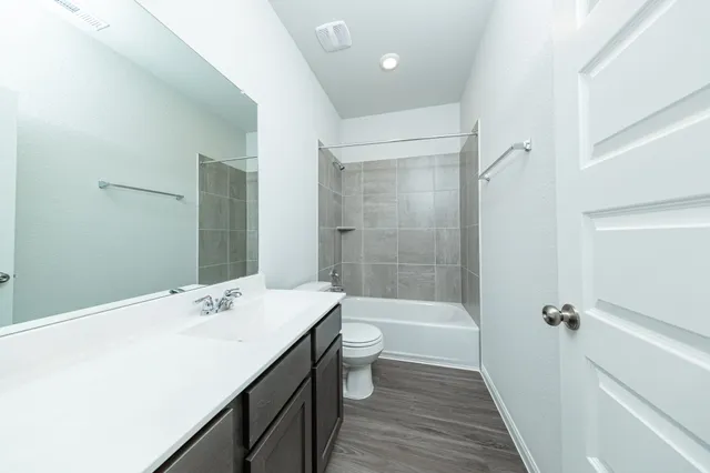 a bathroom with a bathtub shower sink mirror vanity and toilet