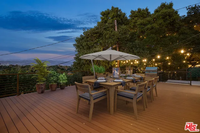 a view of a patio with a dining table and chairs under an umbrella with a patio
