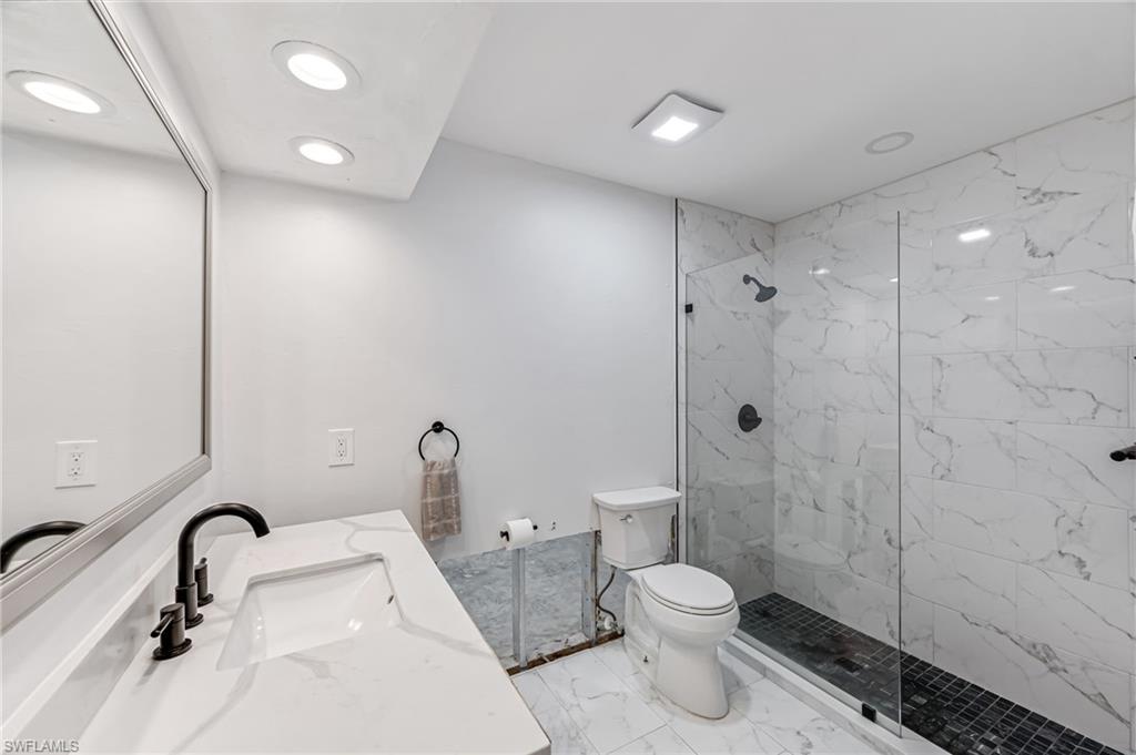 2472 Harbor Road Naples, FL 34104 - Photo 10 of 29 Bathroom featuring a tile shower, vanity, and toilet