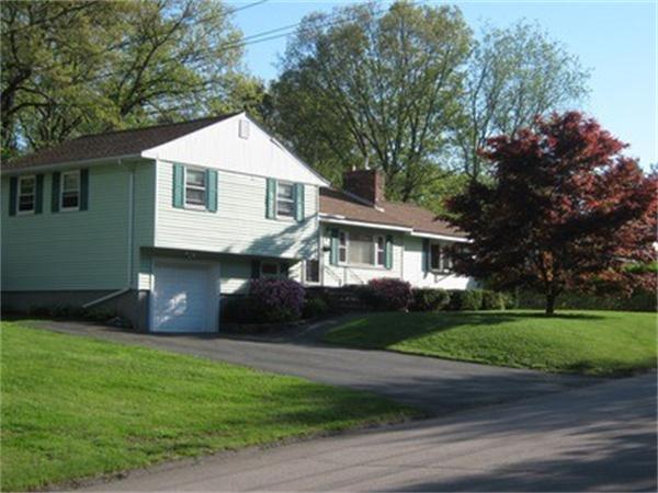 a front view of a house with a garden and trees