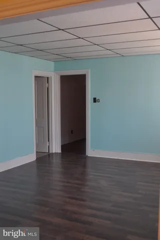 a view of an empty room with wooden floor and closet