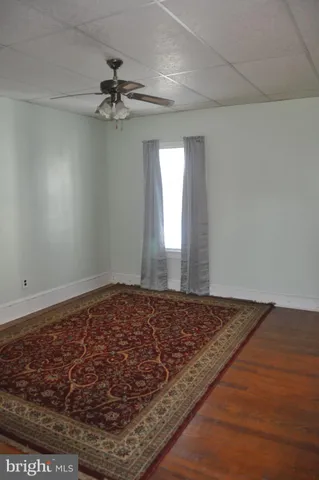 a view of a room with a ceiling fan and hardwood floor