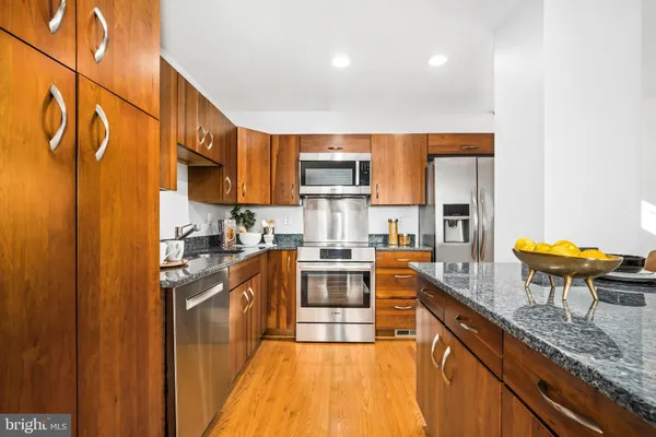a kitchen with granite countertop stainless steel appliances a stove microwave and sink