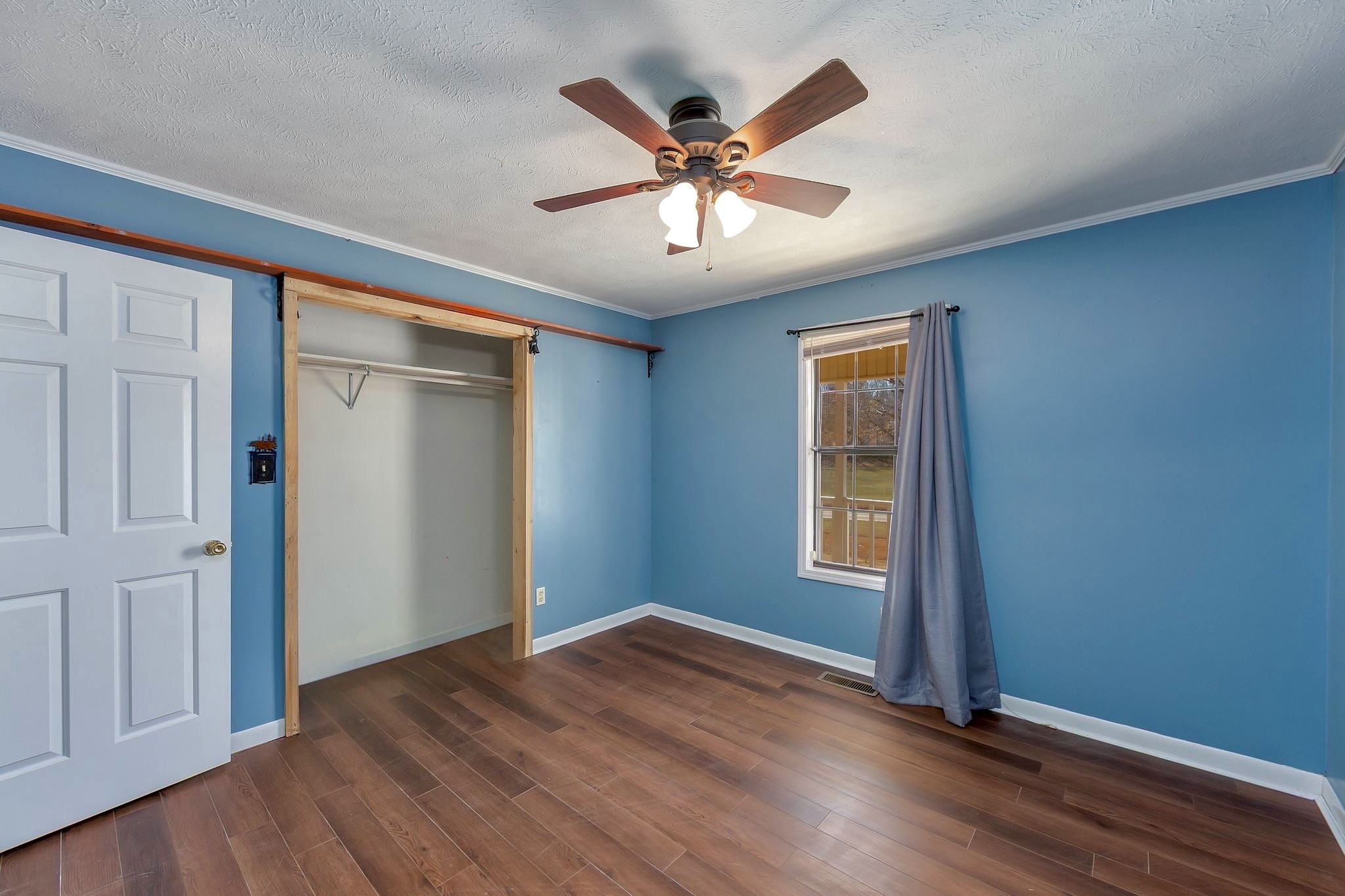 6675 Highway 100 Reagan, TN 38368 - Photo 16 of 32 an empty room with wooden floor ceiling fan and windows