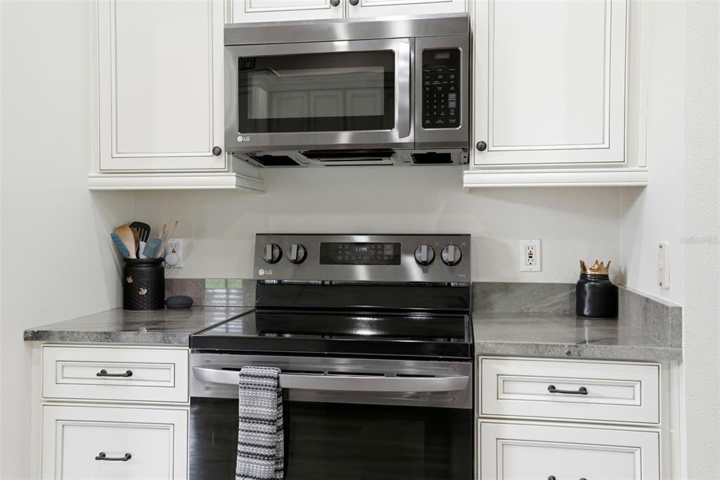 11437 Deercroft Court Spring Hill, FL 34609 - Photo 10 of 37 a kitchen with stainless steel appliances granite countertop white cabinets and a stove top oven