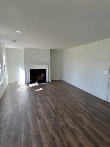 an empty room with wooden floor fireplace and windows