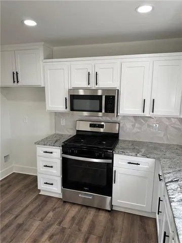 a kitchen with stainless steel appliances white cabinets and a stove top oven