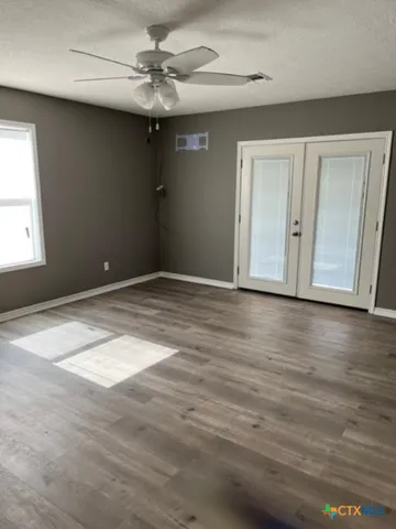 a view of an empty room with window and wooden floor