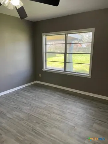 a view of an empty room with wooden floor and a window