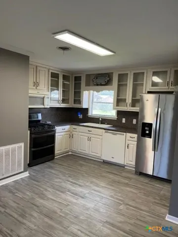 a kitchen with granite countertop a refrigerator and a stove top oven