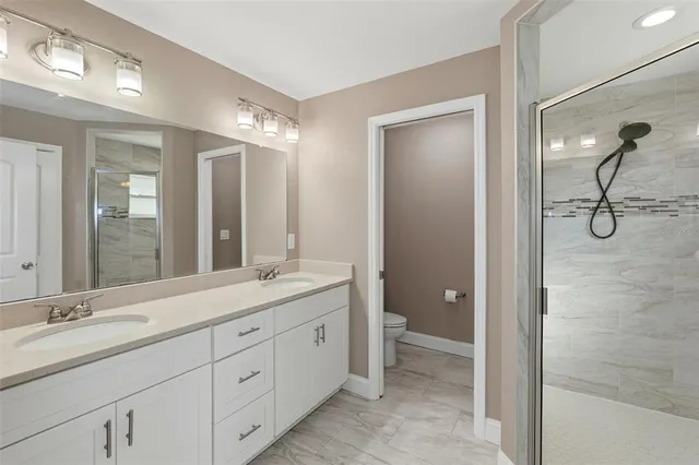 a bathroom with a double vanity sink and mirror with shower