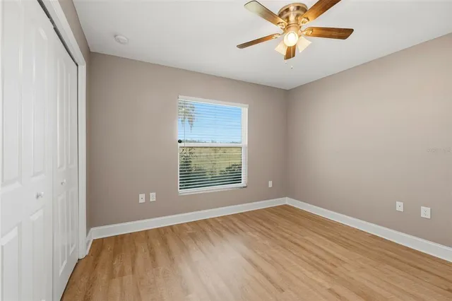 a view of an empty room with window and a chandelier fan