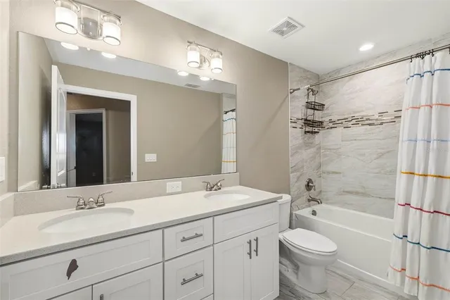 a bathroom with a double vanity sink toilet mirror and bathtub