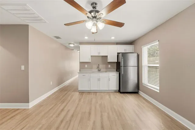 a kitchen with refrigerator a stove and white cabinets