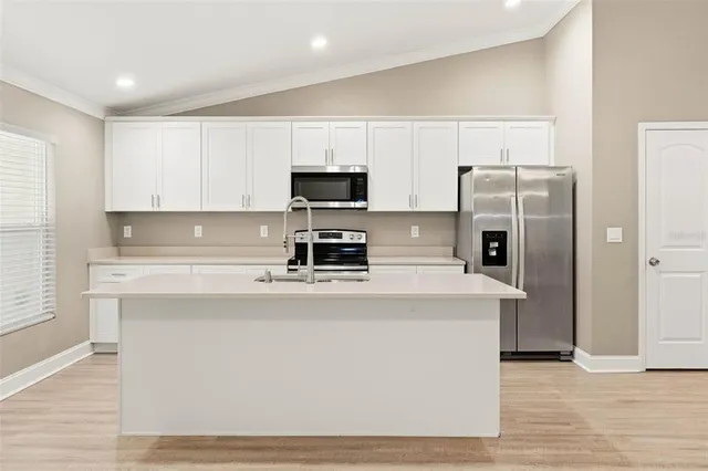 a kitchen with stainless steel appliances a refrigerator a stove a sink and white cabinets