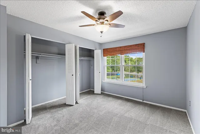 a view of an empty room with a ceiling fan and window
