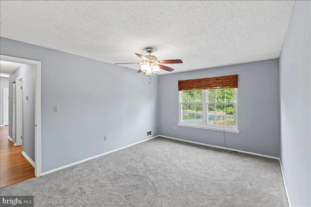 an empty room with a window and a ceiling fan