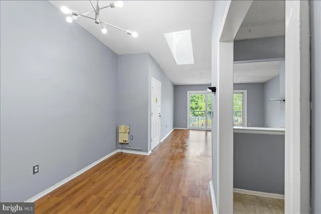 a view of an empty room with window and wooden floor