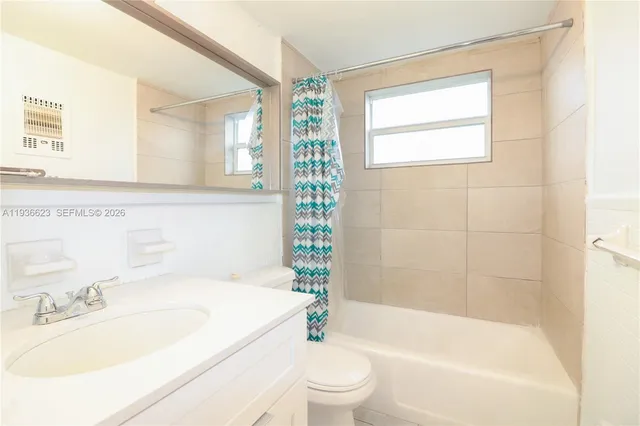 a bathroom with a granite countertop bathtub shower sink vanity mirror and toilet