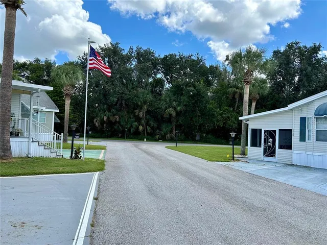 a view of a house with a big yard and palm trees