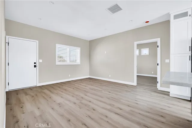 a kitchen with stainless steel appliances granite countertop a refrigerator a sink a stove and white cabinets with wooden floor