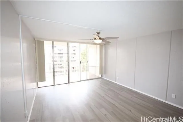 an empty room with wooden floor fan and windows