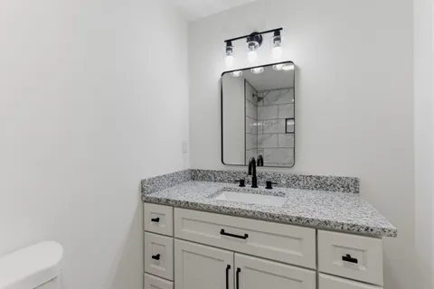 a bathroom with a granite countertop sink and a mirror