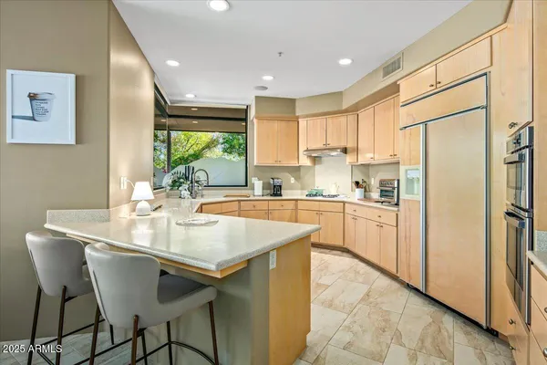a kitchen with stainless steel appliances granite countertop a table chairs sink and cabinets