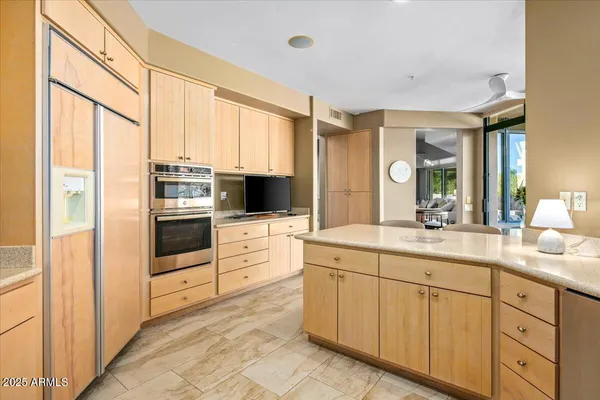 a kitchen with stainless steel appliances kitchen island granite countertop a refrigerator and cabinets