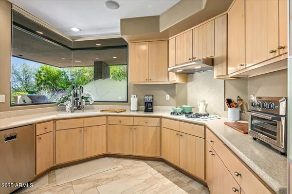 a kitchen with kitchen island granite countertop a sink stainless steel appliances and cabinets