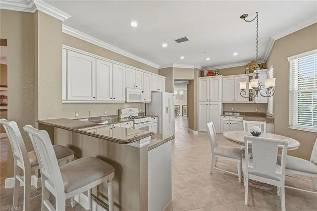 a kitchen with stainless steel appliances granite countertop a table chairs sink and cabinets