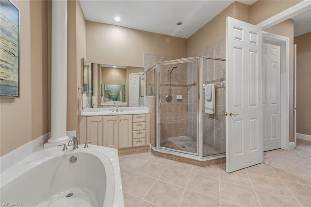 a bathroom with a tub shower sink vanity granite and mirror