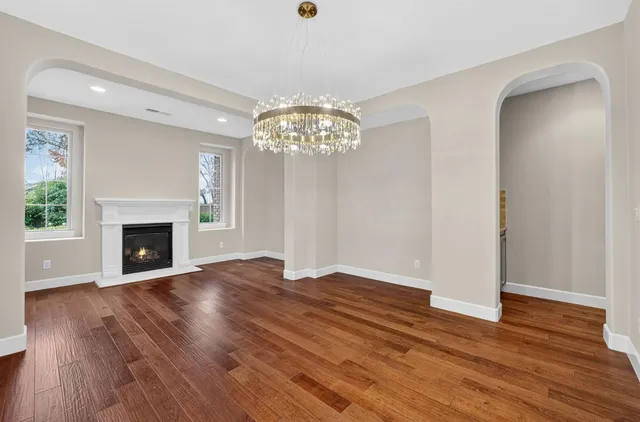 a view of an empty room with wooden floor fireplace and a window