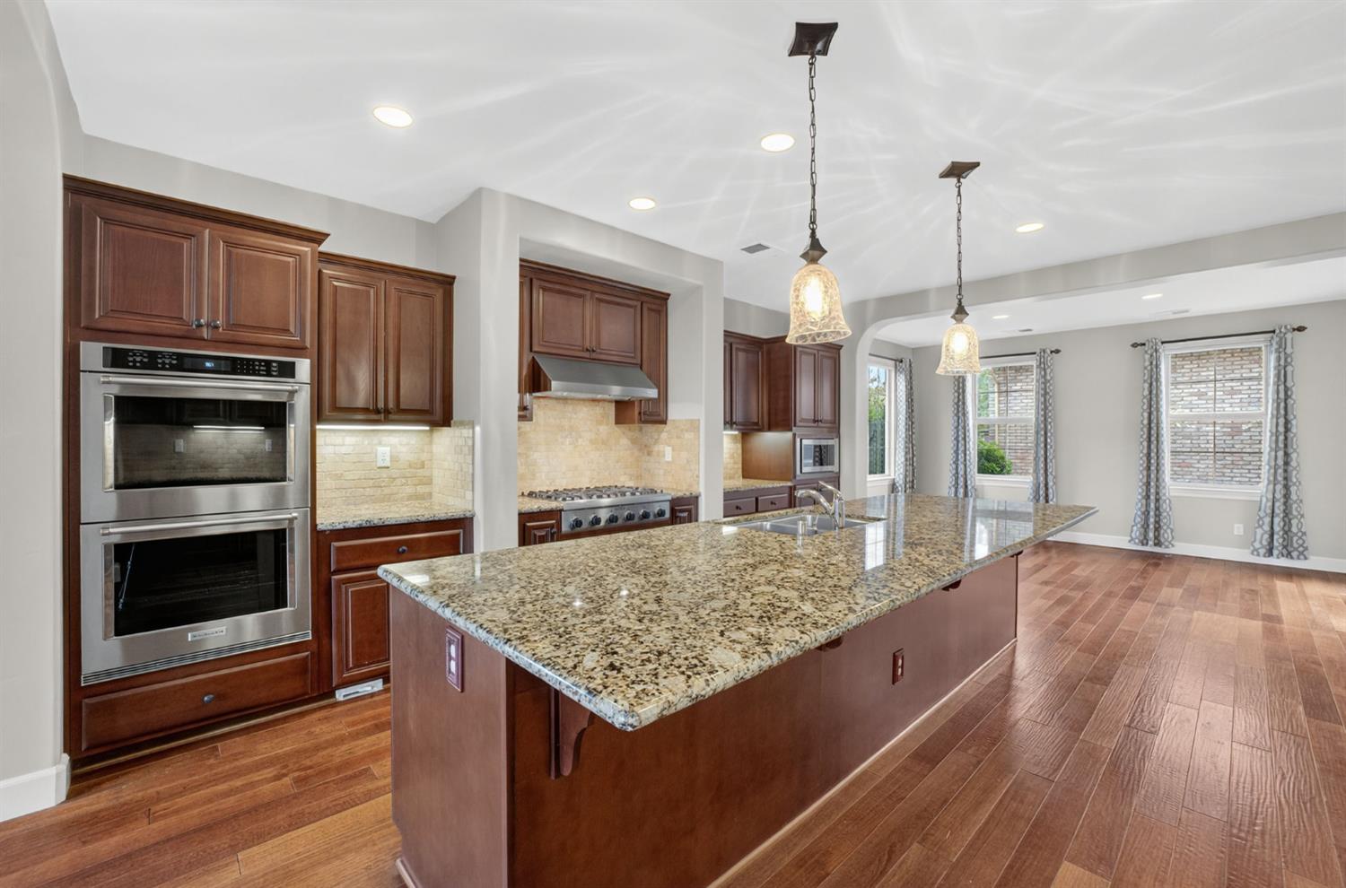 2050 Impressionist Way El Dorado Hills, CA 95762 - Photo 22 of 83 a kitchen with kitchen island granite countertop a stove oven and a wooden floors