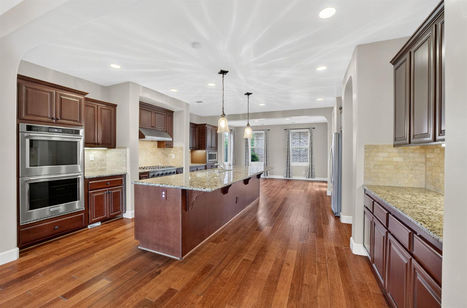 2050 Impressionist Way El Dorado Hills, CA 95762 - Photo 26 of 83 a large kitchen with stainless steel appliances wooden floor and wooden cabinets