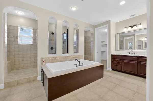 a spacious bathroom with a tub double sink shower and mirror