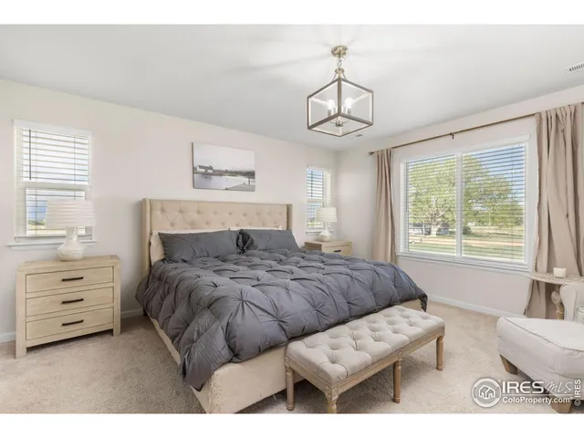 a bedroom with a bed a chandelier and a dresser