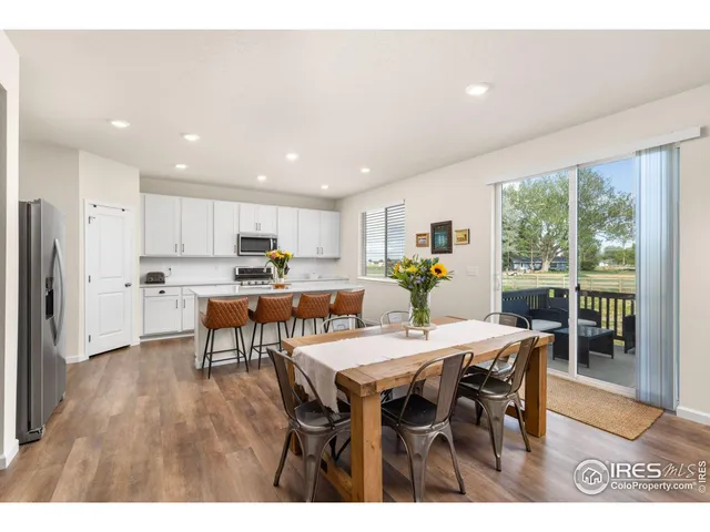 a open dining room with stainless steel appliances kitchen island granite countertop a dining table chairs and granite counter tops