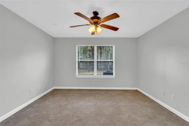an empty room with window and ceiling fan