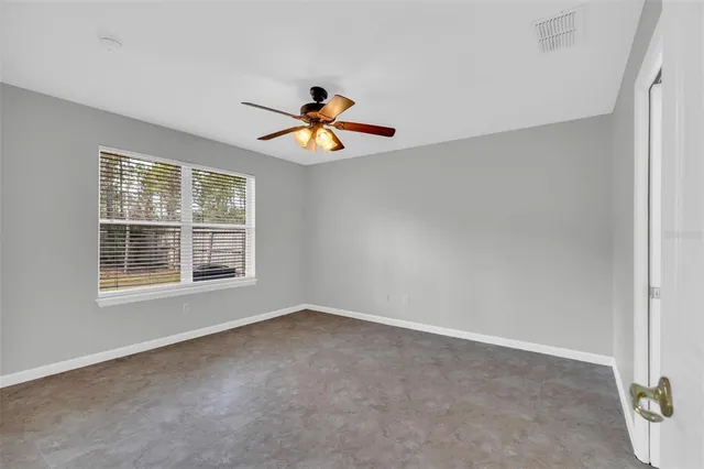 an empty room with a window and a ceiling fan