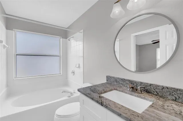 a bathroom with a granite countertop sink mirror vanity and bathtub