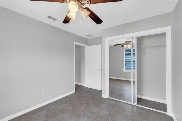 an empty room with closet and a chandelier fan