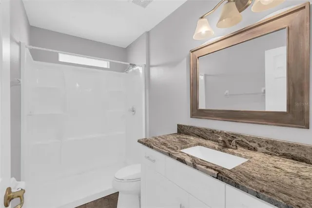 a bathroom with a granite countertop sink and a mirror