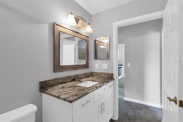 a bathroom with a granite countertop sink and a mirror
