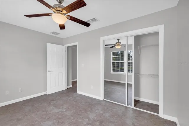 an empty room with closet and a ceiling fan