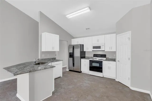 a kitchen with stainless steel appliances granite countertop a stove refrigerator and a sink
