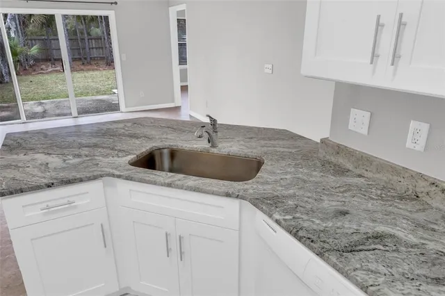 a kitchen with granite countertop a sink and a white cabinets